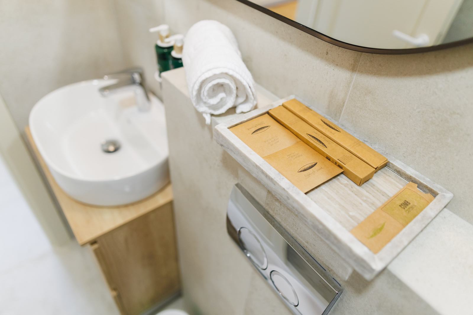 Chiuvetă cu prosoape și tavă cu articole de toaletă.