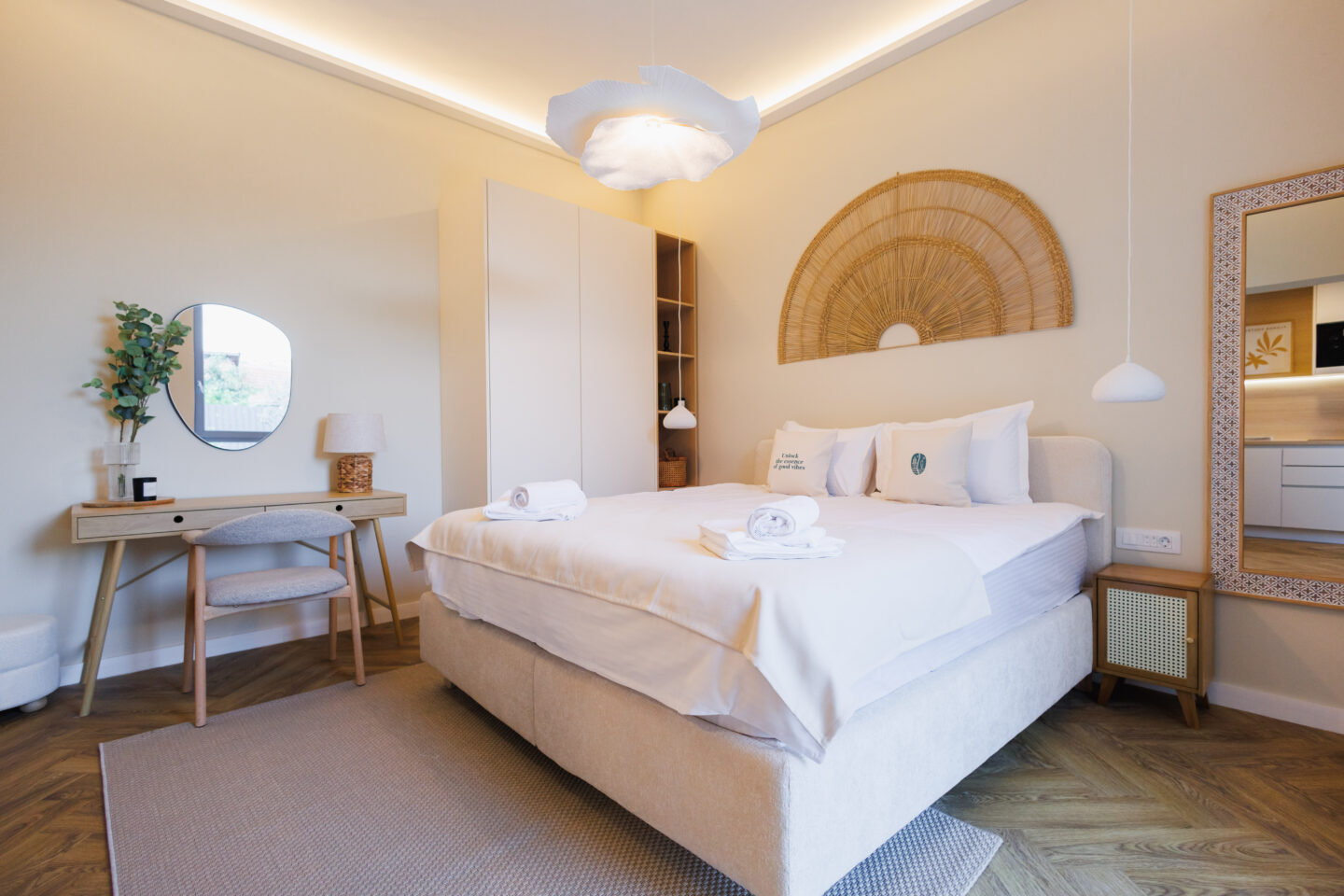 Living premium cu tapet tropical, canapea albă și bucătărie deschisă.